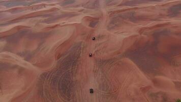 A drone flies over quad bikes driving through the sand dunes of the desert in the United Arab Emirates. Aerial view video