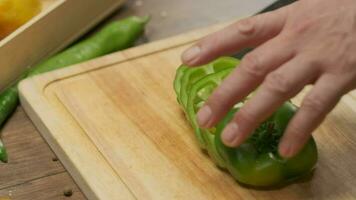 professioneel chef bereidt zich voor en bezuinigingen groen klok peper. dichtbij omhoog langzaam beweging video