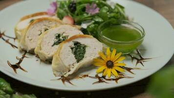 Chicken roll with spinach nicely served on a plate with greens, flower decorations and green oil video