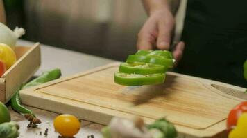 professioneel chef bereidt zich voor en bezuinigingen groen klok peper. dichtbij omhoog langzaam beweging video