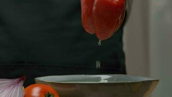 Professional chef prepares and cuts red bell pepper. Close up slow motion video