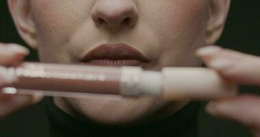 fermer de Jeune élégant femme avec une tube de rouge à lèvres dans sa mains. lent mouvement, studio tir. video