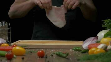Professional chef salting chicken fillet steak, close up slow motion video