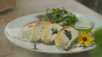 Chicken roll with spinach nicely served on a plate with greens, flower decorations and green oil video