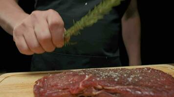 professioneel chef is van toepassing Groenen naar vlees steak. langzaam beweging dichtbij omhoog. video