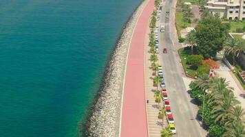 A drone flies over a road along the seashore near Dubai, United Arab Emirates. Aerial video