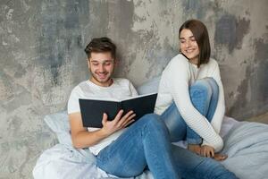 young happy smiling couple sitting on bed at home photo