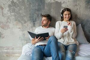 young happy smiling couple sitting on bed at home photo