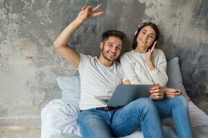 joven contento sonriente Pareja sentado en cama a hogar foto