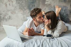 young happy smiling couple sitting on bed at home photo