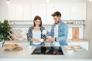 young happy man and woman in kitchen, breakfast, couple together in morning, smiling, having tea photo