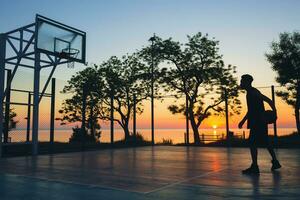 black man doing sports, playing basketball on sunrise, silhouette photo