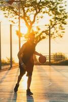 black man doing sports, playing basketball on sunrise, active lifestyle, sunny summer morning photo