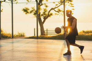 black man doing sports, playing basketball on sunrise, active lifestyle, sunny summer morning photo