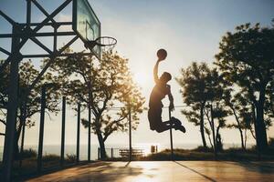 black man doing sports, playing basketball on sunrise, jumping silhouette photo