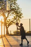 negro hombre haciendo Deportes, jugando baloncesto en amanecer, activo estilo de vida, soleado verano Mañana foto