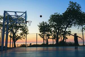 negro hombre haciendo Deportes, jugando baloncesto en amanecer, silueta foto