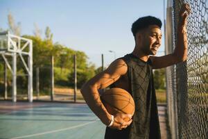 negro hombre haciendo Deportes, jugando baloncesto en amanecer, activo estilo de vida, soleado verano Mañana foto