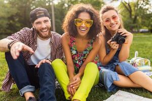 happy young company of talking smiling friends sitting park photo