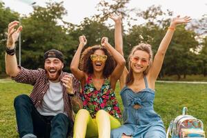 happy young company of talking smiling friends sitting park photo