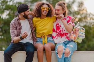 happy young company of smiling friends sitting in park photo