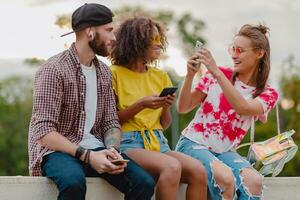 happy young company of smiling friends sitting in park photo