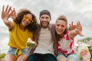 happy young company of smiling friends sitting in park photo