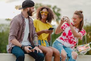 happy young company of smiling friends sitting in park photo