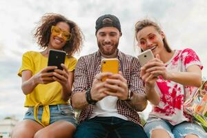 happy young company of smiling friends sitting in park photo