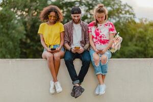 happy young company of smiling friends sitting in park photo