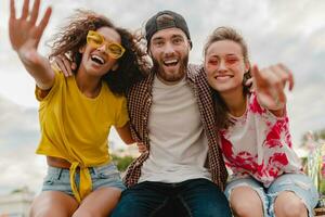 happy young company of smiling friends sitting in park photo