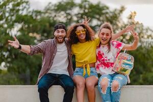 happy young company of smiling friends sitting in park photo