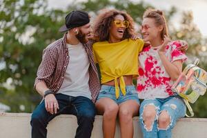 happy young company of smiling friends sitting in park photo