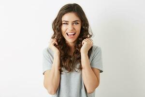 portrait of young pretty woman in t-shirt laughing, holding hands up, isolated, happy, long curly hair, white teeth photo