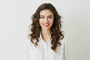 close-up portrait of smiling attractive woman with white teeth, long curly hair, red lipstick make-up looking in camera isolated wearing white blouse photo