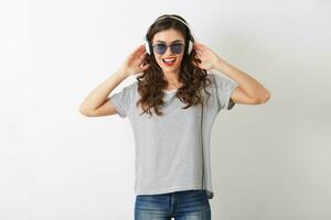young attractive woman listening to music on headphones, wearing sunglasses, isolated on white background, photo