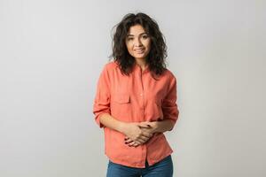 retrato de joven atractivo confidente mujer en naranja camisa, Rizado cabello, sonriente, feliz, natural mirar, verano estilo, Moda tendencia, participación su manos juntos, mirando en cámara, mezclado carrera, aislado foto