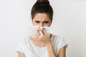 close-up portrait of pretty woman blowing her nose with napkin, catch a cold, feeling sick, isolated, white studio background, frowning photo