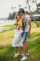 young stylish hipster couple in love holding a dog at the tropical park photo