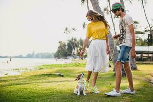 young stylish hipster couple in love holding a dog at the tropical park photo