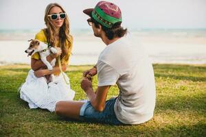 young stylish hipster couple in love holding a dog at the tropical park photo