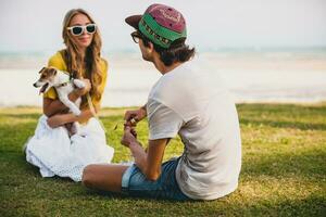 young stylish hipster couple in love holding a dog at the tropical park photo