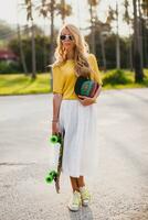 hipster cool woman with skate board and cap posing smiling on vacation photo