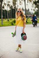 hipster cool woman with skate board and cap posing smiling on vacation photo