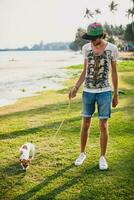 joven elegante hipster hombre caminando jugando perro perrito Jack Russell foto