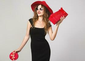 young beautiful woman holding presents, black dress, red hat photo