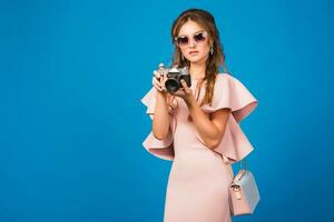 young stylish sexy woman in pink luxury dress taking pictures on vintage camera photo