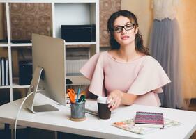 woman in pink luxury dress, summer trend, fashion designer working at office on computer photo