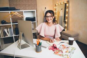 woman in pink luxury dress, summer trend, fashion designer working at office on computer photo