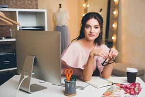 woman in pink luxury dress, summer trend, fashion designer working at office on computer photo